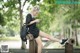 A woman sitting on top of a wooden post looking at her phone.