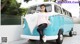 A woman sitting on the back of a blue and white van.