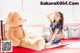 A woman sitting on a bed next to a large teddy bear.