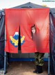 A woman standing in front of a tent holding a flag.