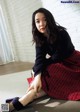 A woman sitting on the floor wearing a red skirt and black sweater.