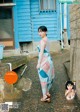 A woman standing in front of a blue building.