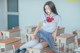 A woman sitting on top of a desk in a classroom.