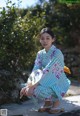 A woman in a kimono crouching down with a fan.