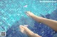 A woman's feet in a swimming pool with a pink flower floating in the water.