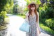 A woman in a dress and hat holding a blue bag.