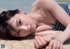 A woman laying on the beach in a bikini.