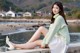 A woman sitting on a concrete wall by the water.