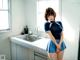 A woman in a blue uniform standing in a kitchen.