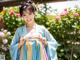 A woman in a blue and pink dress standing in front of flowers.