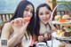 Two young women sitting at a table with plates of food.