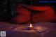 A woman laying on a bed next to a lit candle.