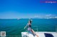 A woman sitting on the bow of a boat in the ocean.