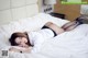 A woman laying on a bed in a white shirt and black stockings.