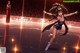 A woman in a blue dress skating on a ice rink.